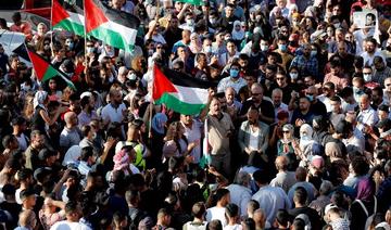 Des Palestiniens lèvent des pancartes et des drapeaux nationaux alors qu'ils se rassemblent dans la ville de Ramallah en Cisjordanie occupée, le 26 juin 2021, pour protester contre la mort du militant des droits humains Nizar Banat (Photo, AFP)