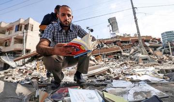 Un Palestinien feuillette un livre qu’il a trouvé dans les décombres de l’immeuble Kuhail, qui abritait la librairie Samir Mansour, dans la ville de Gaza (Photo, AFP) 