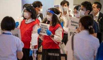 Le personnel d'accueil des délégations olympiques tient des pancartes dans le hall des arrivées de l'aéroport international de Tokyo le 8 juillet 2021, avant les Jeux olympiques. (Kazuhiro Nogi/AFP)