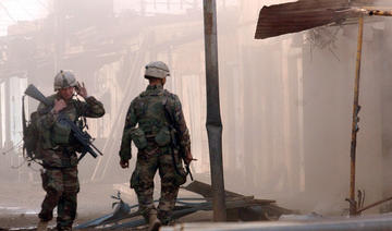 Deux soldats américains inspectant les dégâts après qu'une petite charge explosive a été utilisée pour faire sauter la porte d'un magasin, dans le quartier industriel de Samarra, le 17 décembre 2003. (Fichier/AFP) 