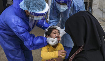 Une jeune fille réagit au moment où un professionnel de la santé effectue un prélèvement nasal dans une clinique à l’occasion d’un dépistage de Covid-19 dans la ville de Gaza. (AFP/File Photo)