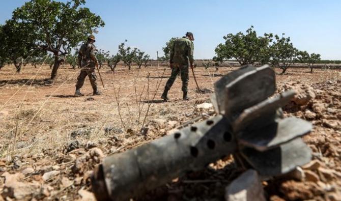 Des soldats de l'armée syrienne utilisent des détecteurs pour trouver et éliminer des mines terrestres dans un champ d'un verger de pistaches dans le village de Maan, au nord de Hama, dans le centre-ouest de la Syrie, le 24 juin 2020 (Photo, AFP)