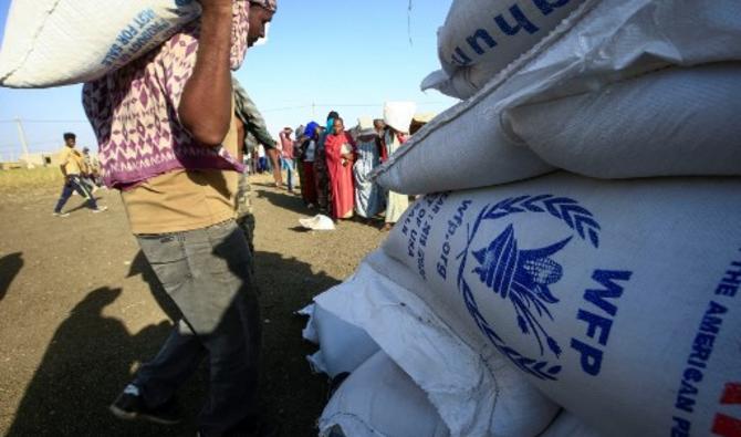 Des réfugiés éthiopiens qui ont fui les combats dans la région du Tigré regardent les travailleurs décharger l'aide alimentaire du Programme alimentaire mondial au centre d'accueil frontalier Village 8 dans l'État soudanais de Gedaref, le 20 novembre 2020 (Photo, AFP)