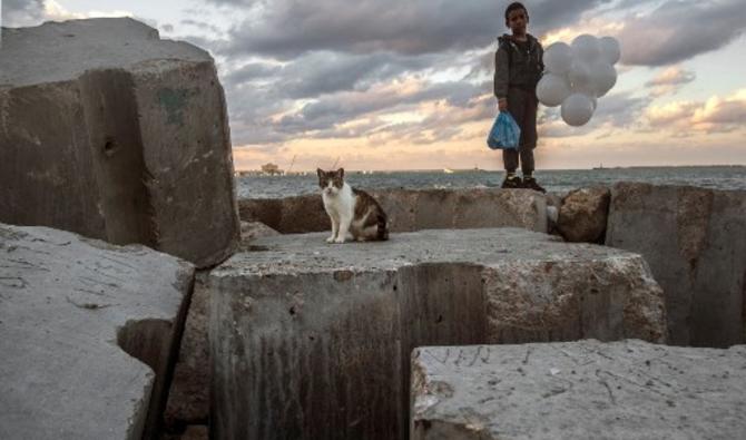 Un chat et un enfant sur des blocs de béton au bord de la mer Méditerranée dans le port historique d'Alexandrie, dans le nord de l'Égypte, le 26 mars 2021.(Khaled Desouki/AFP)