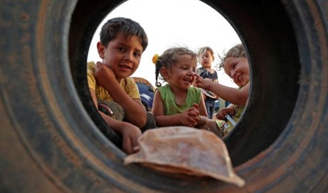Des enfants syriens jouent avec un pneu dans un camp pour personnes déplacées à l'intérieur de la ville de Maaret Misrin, dans la province d'Idlib, dans le nord-ouest de la Syrie, le 8 mai 2021 (Photo, AFP)