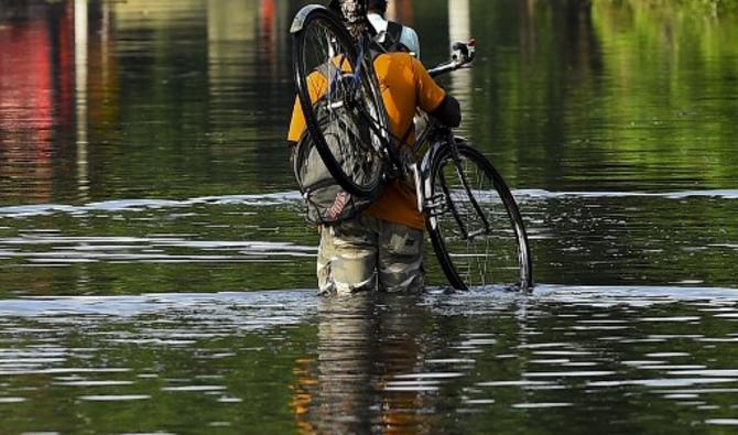 Un habitant porte son vélo alors qu'il marche dans les eaux de crue après de fortes pluies de mousson à Kelaniya, à la périphérie de Colombo, le 6 juin 2021 (Photo, AFP)