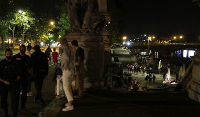 Des gens se tiennent sur les rives de la Seine après le couvre-feu Covid-19 de 23 heures, tôt le 12 juin 2021, après que des personnes se soient rassemblées à proximité, aux Invalides, pour une fête en plein air non autorisée (AFP) 