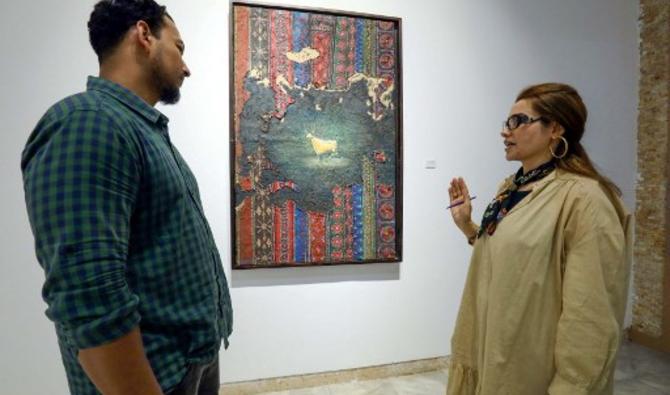 Un visiteur s'entretient avec l'artiste libyenne Elham el-Ferjani devant l'une de ses œuvres à la galerie Hamim de la ville orientale de Benghazi, le 14 juin 2021 (Photo, AFP)