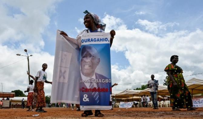Une femme s'enveloppe d'une banderole à l'effigie de l'ancien président ivoirien Laurent Gbagbo avant son arrivée à Mama le 27 juin 2021 (Photo, AFP)