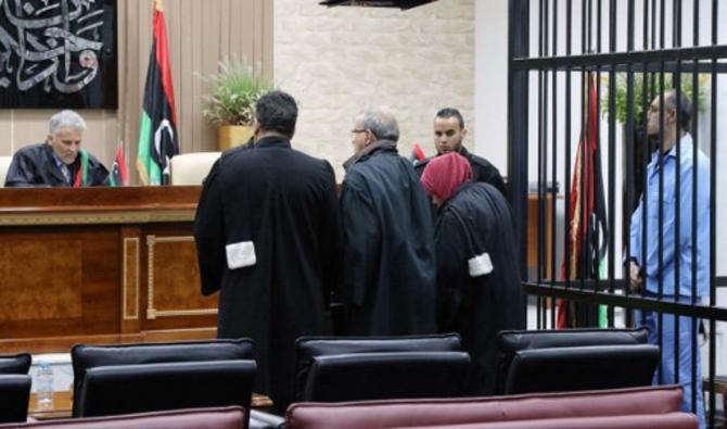 Saadi Kadhafi (à droite), le fils du dirigeant déchu Mouammar Kadhafi, se tient dans la cellule de l'accusé lors de son procès dans un palais de justice de la capitale libyenne Tripoli, le 13 mars 2016 (Photo, AFP)