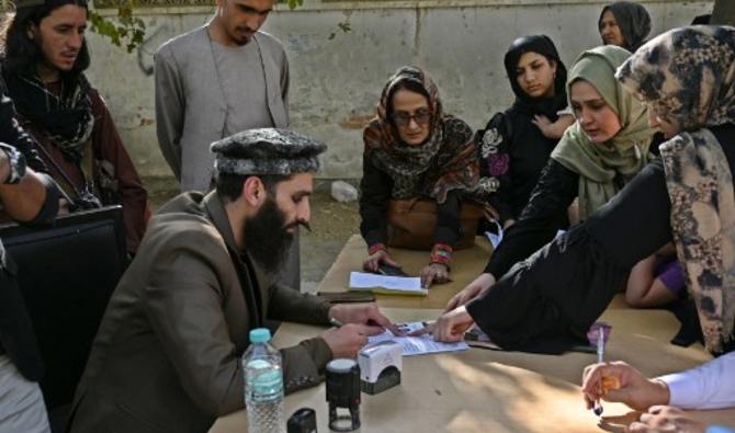 Un travailleur vérifie les documents des personnes après que les talibans ont annoncé la réouverture des demandes de passeport, devant le bureau des passeports de Kaboul, le 6 octobre 2021 (Photo, AFP)