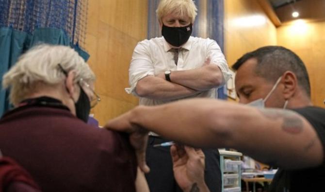 Le Premier ministre britannique Boris Johnson regarde Nitza Sarner, 88 ans, recevoir un rappel de vaccination Pfizer-BioNTech au Little Venice Sports Centre à Londres, le 22 octobre 2021 (Photo, AFP)