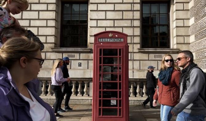 Des piétons passent devant une cabine téléphonique rouge dans le centre de Londres, le 26 octobre 2021 (Photo, AFP)