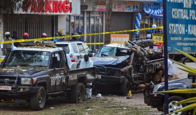 Des policiers en équipement de protection individuelle (ÉPI) enquêtent autour des voitures de police détruites par l'explosion d'une bombe devant le commissariat central de Kampala, en Ouganda, le 16 novembre 2021. (Photo, AFP)