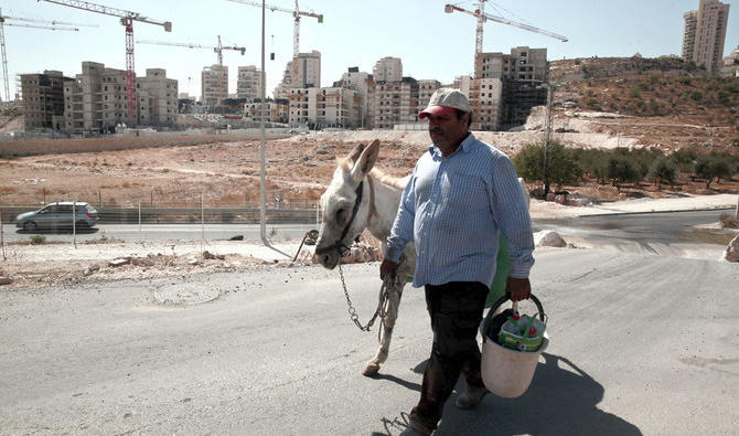 Un Palestinien marchant près d’un chantier de construction de nouveaux logements israéliens dans le quartier de Har Homar, à Jérusalem-Est, en septembre 2016. (Photo AP) 