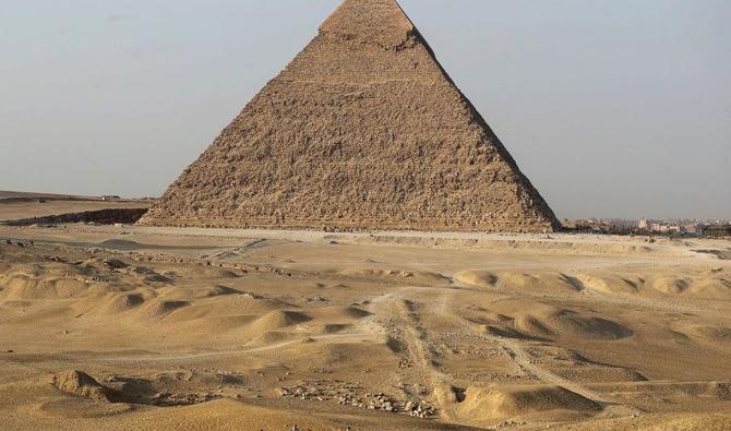Des touristes se promènent à dos de chameau près des grandes pyramides de Gizeh, à la périphérie du Caire, le 23 octobre 2021. (Reuters) 