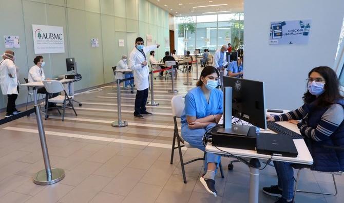 Un infirmier aide une patiente pendant que d'autres attendent dans un couloir du Rafic Hariri University Hospital, au Liban, qui imposera un couvre-feu nocturne à partir du 17 décembre et pendant trois semaines aux personnes non vaccinées. (STR/AFP via Getty Images) 