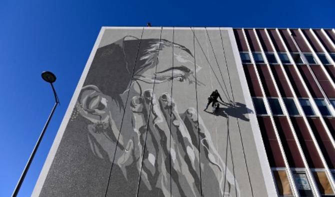 L'artiste de rue français Mahn Kloix peint une fresque représentant Tursunay Ziawudum, une ancienne détenue ouïghoure qui a quitté la Chine et a parlé publiquement de son expérience d'internement, à Marseille, dans le sud de la France, le 7 octobre 2021. (Nicolas Tucat/AFP)