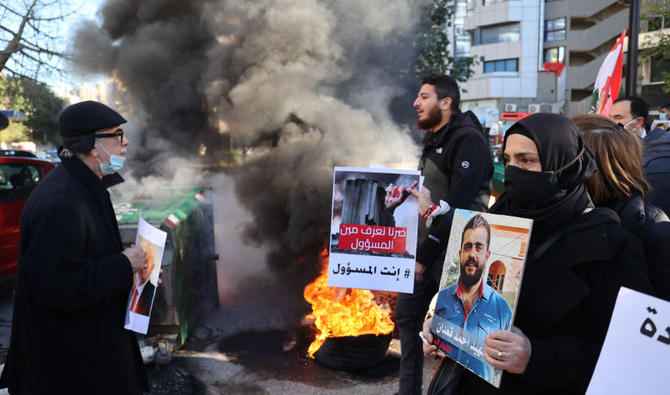 Des parents libanais de victimes de l'explosion du port de Beyrouth du 4 août 2020 brandissent les portraits de leurs proches décédés dans l'explosion massive, tandis que d'autres brûlent des pneus lors d'un sit-in devant le palais de Justice, à Beyrouth, le 17 janvier 2022. (Photo, AFP)
