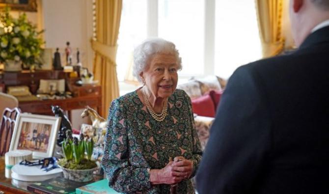 La reine Elizabeth II souriante, portant une robe à motifs, une canne dans les mains. Le 16 février 2022.(Photo, AFP)