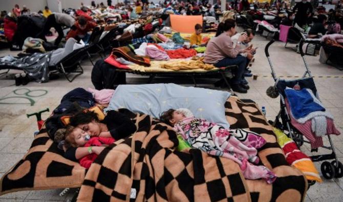 Une mère dort avec ses enfants parmi tant d'autres dans un abri temporaire accueillant des réfugiés ukrainiens situé dans un ancien centre commercial près de la ville de Przemysl, le 8 mars 2022. (Photo, AFP)