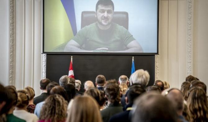 Le président ukrainien Volodymyr Zelensky est vu sur un écran alors qu'il s'exprime dans une vidéo diffusée aux membres du Parlement danois au château de Christiansburg à Copenhague, le 29 mars 2022. (Photo, AFP)