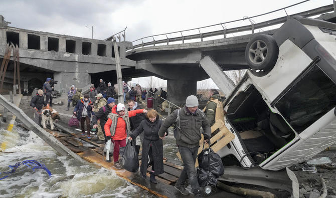 Des personnes traversent un chemin improvisé sous un pont détruit en fuyant la ville d'Irpin près de Kiev, en Ukraine, le lundi 7 mars 2022. (Photo, AP)