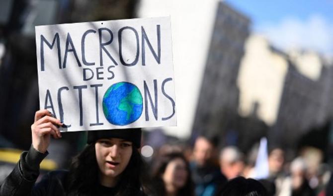 Une manifestante tient une pancarte indiquant «Macron, quelques actions», pour appeler les candidats à la présidentielle à prendre en compte l'urgence climatique, le 12 mars 2022. (Photo, AFP) 