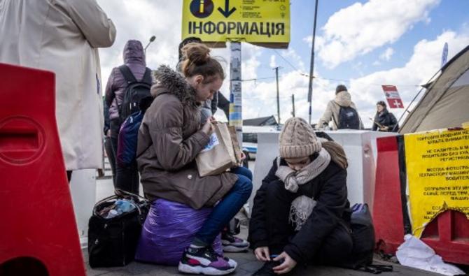 Des jeunes filles et d'autres réfugiés ukrainiens attendent le bus après avoir traversé la frontière ukraino-polonaise au poste frontière de Medyka, dans le sud-est de la Pologne, le 8 avril 2022. (Photo, AFP)