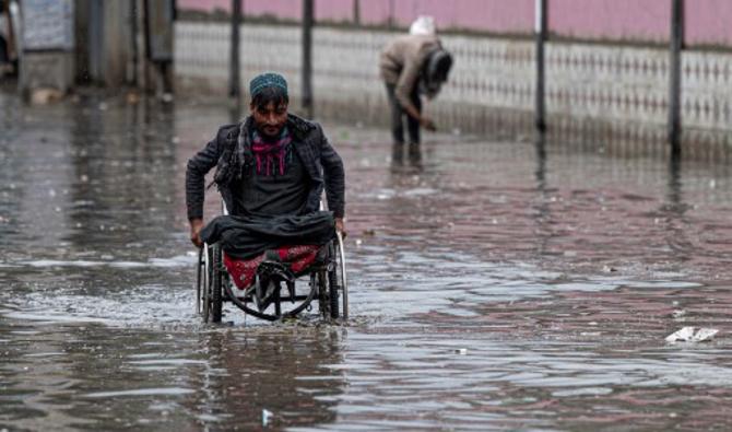 Un homme en fauteuil roulant traverse les eaux de crue après de fortes pluies dans l'ancien quartier de Kaboul, le 24 avril 2022. (Photo, AFP)