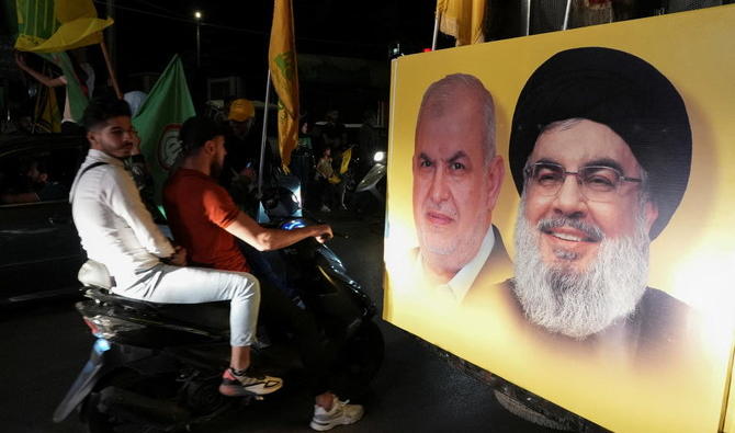 Les partisans portent des drapeaux du Hezbollah et du mouvement Amal à côté d'une affiche représentant le chef du Hezbollah Hassan Nasrallah et le chef du bloc parlementaire du Hezbollah Mohamed Raad lors des élections législatives libanaises de dimanche. (Reuters)