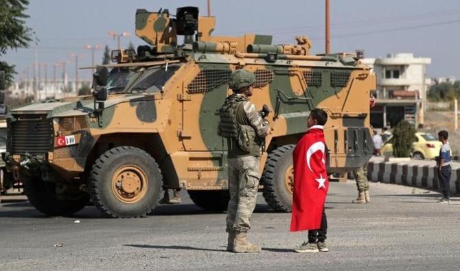 Un garçon portant un drapeau turc se tient à côté d'un soldat turc dans la ville de Tell Abyad, en Syrie, le 23 octobre 2019. (Reuters)