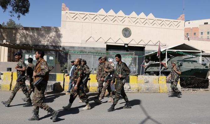 Des miliciens houthis passent devant l’ambassade des États-Unis à Sanaa, au Yémen. (Reuters)