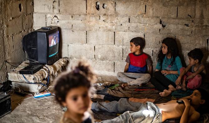 Des enfants syriens, déplacés avec leur famille de Deir Ezzor, regardent la télévision à l'intérieur d'un bâtiment endommagé où ils vivent dans la ville de Raqa, au nord de la Syrie, le 18 juin 2022. (Photo, AFP)