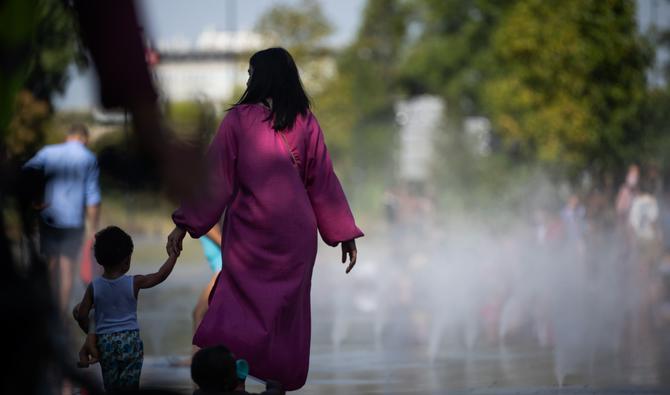 Une femme et un enfant marchent près d'une fontaine à Nantes, le 18 juillet 2022, alors que la température dépasse les 42 degrés Celsius. (Photo, AFP)