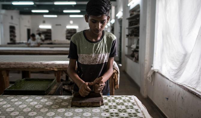 Dans l'imprimerie, six ouvriers œuvrent sur de longues tables, recouvertes de 24 couches de tissu pour ne pas endommager les planches avec lesquelles ils tamponnent la toile de coton. Fermement mais avec délicatesse, ils n'impriment pas plus de 40 mètres de tissus par jour. (Photo, AFP)