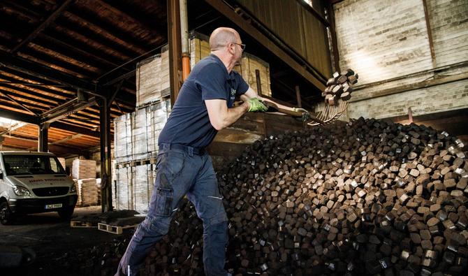 Un ouvrier charge des briquettes de charbon dans le stockage de l'entreprise de produits de chauffage «Hans Engelke Energie» à Berlin, le 10 août 2022. (Photo, AFP)
