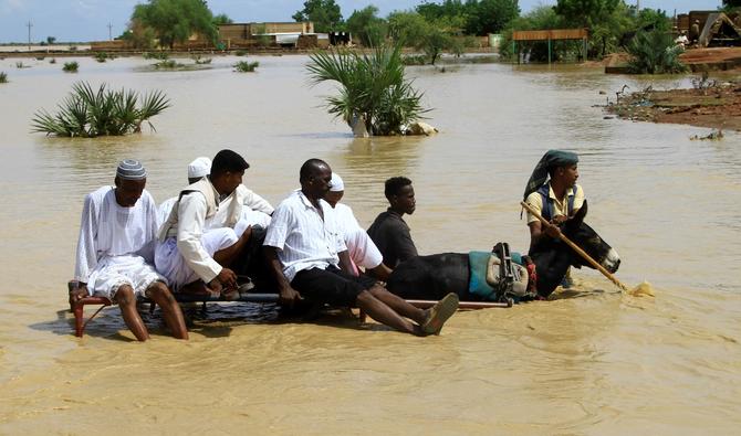 Des Soudanais traversent une route inondée dans la ville d'Iboud, à 250 km au sud de la capitale Khartoum, le 22 août 2022. (Photo, AFP)