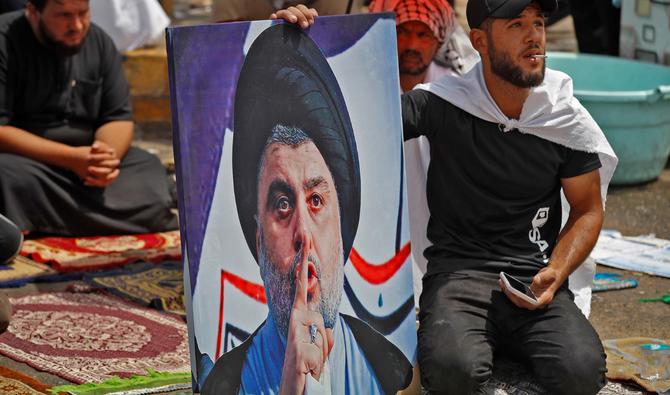 Un partisan du leader chiite irakien Moqtada Sadr est assis avec son portrait lors de la prière hebdomadaire du vendredi lors de la veillée devant le siège du parlement dans la zone verte de haute sécurité de la capitale Bagdad, le 26 août 2022. (Photo, AFP)