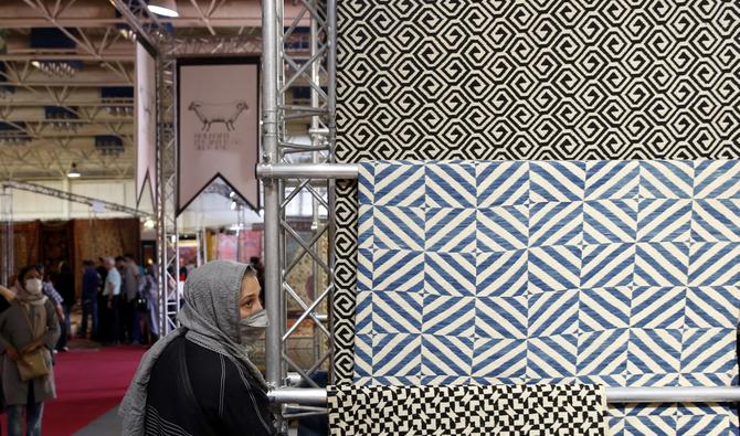 Les gens passent devant une exposition de tapis modernes en laine d'Azerbaïdjan avec des motifs géométriques traditionnels datant du XVIIe siècle lors de la 29e exposition de tapis faits à la main à Téhéran, la capitale iranienne, le 26 août 2022. (Photo, AFP)