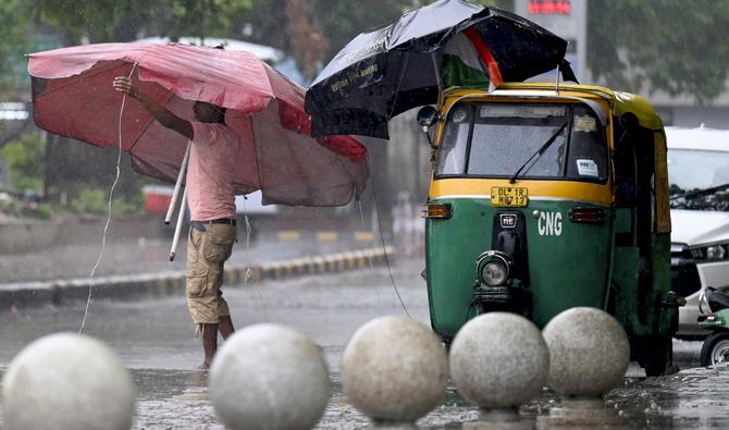 Un vendeur ajuste un parapluie lors d'une averse de mousson à New Delhi, le 4 août 2022. (Photo, AFP)