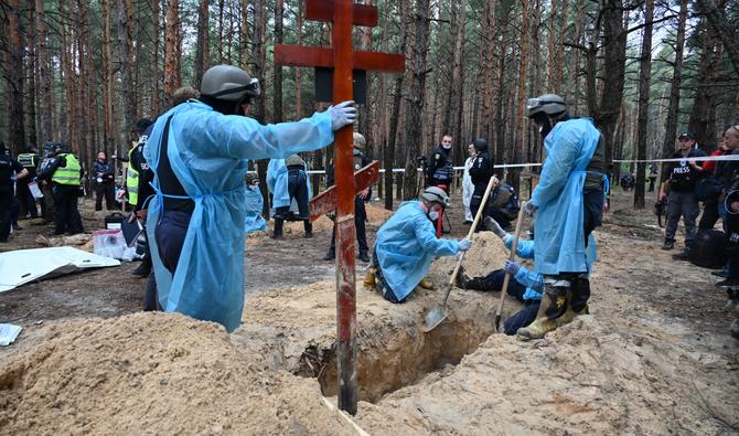 Des techniciens légistes creusent une tombe dans une forêt à la périphérie d'Izyum, dans l'est de l'Ukraine, le 16 septembre 2022. (Photo, AFP)