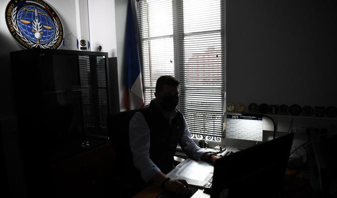 Un gendarme français de l'office chargé des crimes contre l'humanité (OCLCH), travaille dans le bureau, le 21 janvier 2021 à Paris. (Photo, AFP)