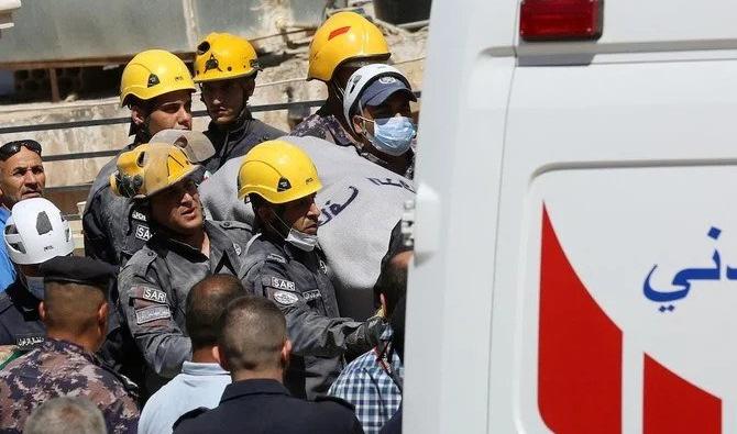 Des secouristes jordaniens transportent un corps dans une ambulance, après l’avoir tiré des décombres d’un immeuble effondré. (Photo, AFP)
