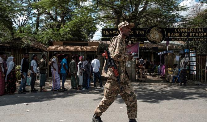 Des gens font la queue devant une banque alors qu'un soldat passe à Alamata, en Éthiopie, le 8 décembre 2020. (Photo, AFP)