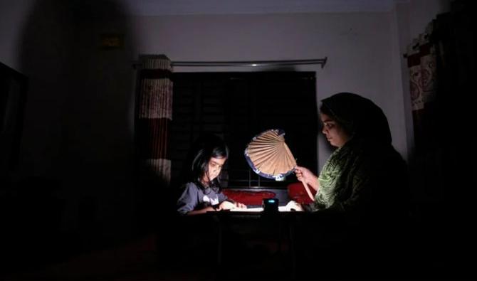 Une femme bangladaise utilise un éventail traditionnel pour aider sa fille dans ses études lors d'une coupure de courant chez elle dans la région de Pilkhana, à Dhaka, au Bangladesh, en août 2022. (Fichier, AP)