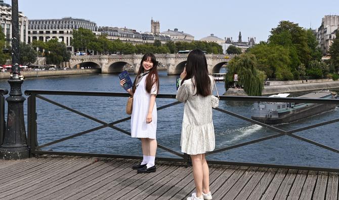 Des touristes prennent des photos sur le pont du «Pont des Arts» à Paris. (Photo, AFP)