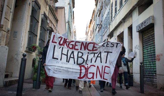 Des personnes tiennent une banderole sur laquelle on peut lire «L'urgence est un logement décent» lors d'un hommage aux victimes décédées dans l'effondrement de deux immeubles de la rue d'Aubagne à Marseille, sud de la France, le 5 décembre 2018. (Photo, AFP)