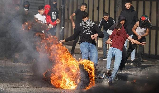 Des Palestiniens manifestent près d’un pneu en feu lors d’affrontements avec les forces israéliennes à Hébron, en Cisjordanie occupée par Israël, dimanche. (Photo, Reuters)Des Palestiniens manifestent près d’un pneu en feu lors d’affrontements avec les forces israéliennes à Hébron, en Cisjordanie occupée par Israël, dimanche. (Photo, Reuters)