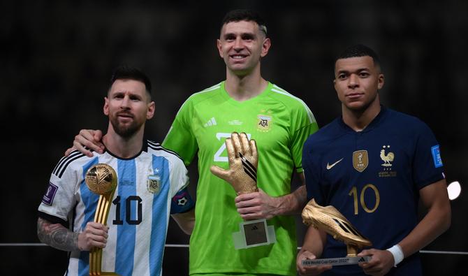 L'attaquant argentin #10 Lionel Messi, le gardien argentin #23 Emiliano Martinez et l'attaquant français #10 Kylian Mbappe posent sur le podium après avoir reçu respectivement le Ballon d'Or, le Gant d'Or et le Soulier d'Or, lors de la cérémonie de remise des trophées de la Coupe du monde Qatar 2022 après la finale de football. (Photo, AFP)